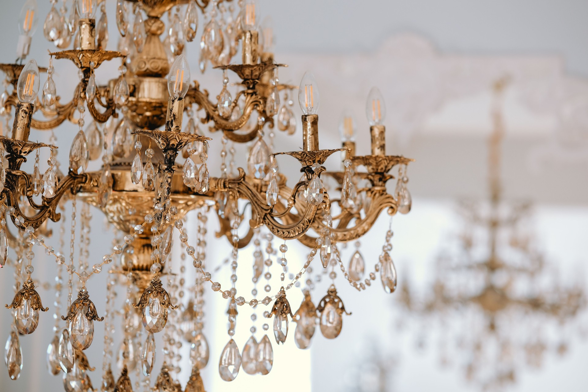 Ornate golden chandelier with crystal embellishments in a bright interior